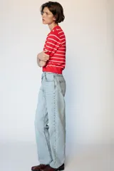 Jeans de tiro alto con diseño de cintura cruzada, cinco bolsillos y pernera recta con bajo sin costura. Cierre frontal con cremallera y botones.