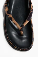 Chancletas planas con estampado de leopardo, tiras finas de dedo y plantilla preformada con acabado de pelo.