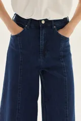 Jean de mezclilla azul oscuro, tiro alto, con pierna muy ancha (palazzo o wide leg) y costuras verticales marcadas en el frente.