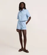 Short runner de mezclilla color celeste, con cintura alta, elástico y lazo ajustable que incluye colgantes decorativos de piña, además de bolsillos estilo carpintero.