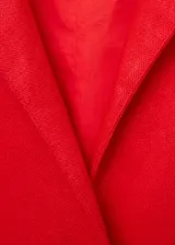 Mono camisero color rojo coral, sin mangas, confeccionado en lino. Presenta cuello camisero, cierre frontal cruzado, cinturón trenzado desmontable y corte palazzo.