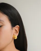 Aros tipo stud dorados con diseño acanalado en forma de espiral.