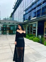 Blusa negra con escote off-shoulder y mangas largas ajustadas.