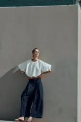 Pantalón tipo culotte de tiro alto confeccionado en denim azul oscuro. Presenta pinzas delanteras, pernera ancha y corta, bolsillos laterales ocultos y cierre frontal con cremallera, botón y ganchos.