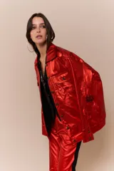 Campera de cuerina metalizada color rojo, con corte oversized, cuello camisero y cierre frontal con botones. Presenta cuatro bolsillos, dos de ellos internos, y logo bordado en las mangas.