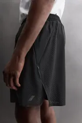 Pantalones cortos negros de tejido técnico perforado, ligeros y elásticos. Cuentan con cintura elástica ajustable con cordón interior, bolsillos frontales, bolsillo trasero de seguridad con cierre de cremallera, perneras con laterales perforados para transpirabilidad, bajo con acabado termofijado y aberturas laterales. Incluye detalle de logo estampado en la pernera.