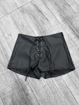 Short negro de cuero sintético con tiro bajo y cordones cruzados en la parte delantera.