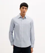 Camisa de vestir para hombre, de manga larga y calce clásico, confeccionada en tricolina de algodón y poliéster, con diseño de cuadros grid en tono celeste claro. Presenta cuello camisero, cierre frontal con botones y puños ajustables con botón único.