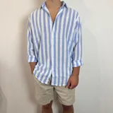 Camisa de lino de corte oversize con diseño de rayas verticales en tonos blanco y tostado, manga larga y cierre frontal con botones.