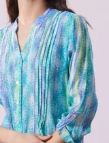 Blusa de gasa estampada multicolor, marca Ruby Rd. Tiene cuello a la base, escote en V, abertura central con botones y plisados en la parte delantera. Las mangas son 3/4 y tienen un largo regulable con presilla y botón.