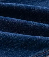 Pantalón de jean corte slim color azul oscuro, con cierre frontal de botón y cremallera, pasadores para cinturón y bolsillos funcionales.