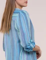 Blusa de gasa de la marca Zac & Rachel, con estampado de rayas verticales en tonos azules, celestes y lilas. Presenta cuello a la base con escote en V, abertura central con botones, detalle plisado en el frente y mangas de largo regulable con presilla y botón.
