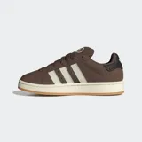 Championes Adidas Campus 00s de color marrón, confeccionados en cuero con las icónicas tres tiras dentadas en color blanco. Presentan una suela de caucho en tono crema y detalles en dorado, con un diseño inspirado en la cultura urbana y el skate de los años 2000.