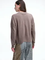 Sweater de tejido de punto color beige, con cuello redondo, hombros caídos y costura central vertical en el frente. Presenta un diseño de corte relajado, con largo asimétrico y aberturas laterales en el ruedo.