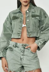 Chaqueta corta de jean verde con botones plateados, cuello clásico y bolsillos frontales.