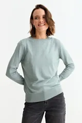 Sweater de punto fino en color verde menta, con cuello redondo, mangas largas y puños acanalados con detalle de botones metálicos laterales.