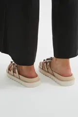 Sandalias chatas de plataforma dentada negra, con múltiples tiras metalizadas decoradas con tachas esféricas brillantes.