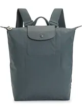Mochila de diseño minimalista en color beige, con cierre superior de cremallera y solapa frontal con botón a presión. Presenta un asa superior y correas ajustables, con el logo de la marca grabado en la solapa.