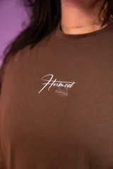 Remera oversize marrón de algodón elastizado con estampado en la espalda que incluye el texto "Crazy Hermod movement" y un diseño de zapatilla alada.