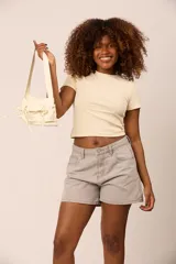 Cartera estilo pocket bag de cuero sintético con acabado brillante, cuenta con bolsillos frontales con cordones ajustables y correa de hombro integrada.