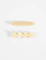 Set de dos broches para el pelo, uno con forma ovalada y otro con cuatro corazones en color crema.