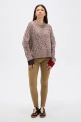Sweater de tejido de punto con efecto jaspeado, corte holgado y cuello redondo. Presenta mangas largas con puños en contraste de color, uno en tono oscuro y otro en tono rojizo.