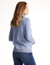 Polera de tejido fino, color rosado, con cuello alto, manga larga y detalle de tajo en los puños.