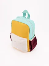 Mochila pequeña de colores, con diseño colorblock en tonos menta, amarillo mostaza, blanco crema y bordó. Presenta un bolsillo frontal con tapa y cierre principal.