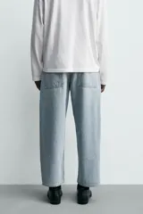 Jeans de hombre color azul claro con efecto lavado, de corte relajado desde la cadera que se estrecha ligeramente en el bajo. Tienen tiro medio, cinco bolsillos y cierre frontal con cremallera y botón.