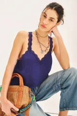 Top negro de viscosa con breteles finos y escote en V con puntilla. Presenta apliques de tachas termo adhesivas en el frente.