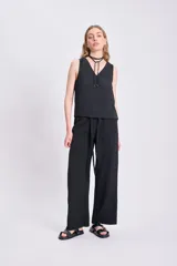 Pantalón negro de corte palazzo con lazo en la cintura y textura arrugada.