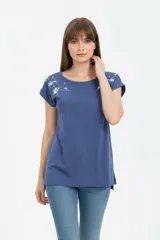Remera de algodón color azul, de corte holgado, cuello redondo a la base y mangas cortas con vuelta. Presenta un delicado estampado floral en color blanco en la zona de los hombros.