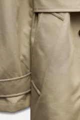 Trench confeccionado en mezcla de algodón color beige. Cuello solapa de muescas y manga larga ajustable con trabillas y botón. Bolsillos en delantero. Cinturón en mismo tejido ajustable con hebilla. Detalle de trabillas en hombros. Cierre frontal cruzado con botones.
