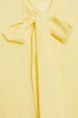 Camisa de rayas finas color amarillo, confeccionada con cuello redondo y lazada en el mismo tejido en el escote. Presenta mangas largas con hombros caídos y puños anchos abotonados.