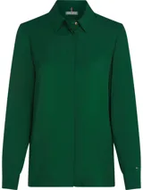 Camisa verde de viscosa con cuello inglés, corte amplio, tapeta oculta, puños abotonados y logo metálico de Tommy Hilfiger en la manga.