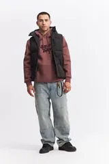 Chaleco puffer negro con capucha, diseño acolchado, cierre frontal y bolsillos laterales funcionales.