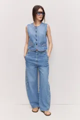 Jean barrel de denim con caída relajada, tiro medio y diseño amplio. Cuenta con apliques de tachas y brillos a los costados de ambas piernas.