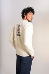 Buzo de cuello redondo color crudo, con detalle de logo bordado en el pecho, mangas largas y puños elastizados.