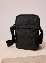Bandolera Rusty modelo Garin de color negro, confeccionada en material textil resistente, con compartimento principal con cierre, bolsillo frontal con solapa y correa ajustable para el hombro.