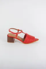 Sandalias de cuero rojo con diseño de tiras horizontales abullonadas en la parte delantera, punta fina, tira vertical central en forma de T y tira ajustable al tobillo. Poseen tacón cuadrado de madera de 6 cm.
