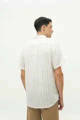 Camisa de manga corta confeccionada en lino y algodón, con fit regular y logo bordado. Color beige con rayas verticales blancas.