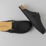 Zuecos negros con plantilla de corcho y hebilla ajustable.
