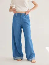 Pantalón jean celeste de corte ancho, con ruedo combinado en un tono más claro.