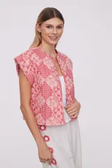 Chaleco corto con estampado geométrico en tonos rosa y rojo, sin mangas y cuello redondo.