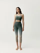 Top deportivo sin mangas de diseño degradado que transiciona de beige en los hombros y pecho a verde oscuro en la parte inferior, con escote redondo y sostén integrado.