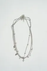 Set de tres collares plateados de diferentes largos. Uno con cadena de eslabones pequeños, otro con cadena de bolitas y el tercero con cadena de eslabones y dijes de hojas.