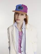Gorro con visera colorblock, con paneles en color marrón, violeta y azul.