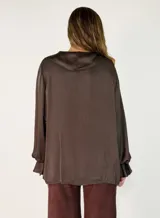Blusa de satén color blanco con escote en V, cuello con volados y mangas largas con puños también decorados con volados.