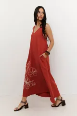 Vestido largo tipo maxi, color terracota, con escote en V, breteles regulables y bolsillos laterales. Presenta un delicado diseño de flores bordadas en hilo crudo en la parte inferior.