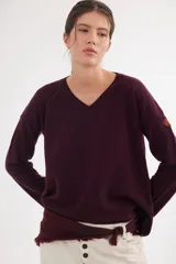 Buzo de escote en V y manga larga, confeccionado en lana lambswool. Presenta un diseño básico con detalle de raya en contratono en una de las mangas, puños y ruedo en color contrastante, y pin metálico de la marca aplicado en la manga.